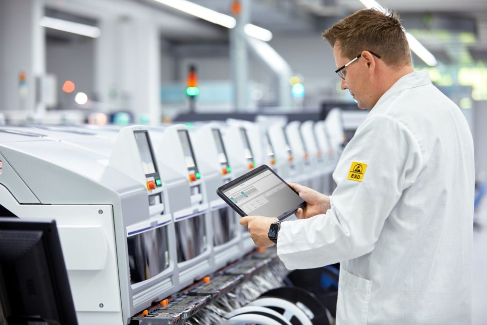 Engineer monitoring industrial production equipment with a tablet in a connected manufacturing environment using legacy OT systems
